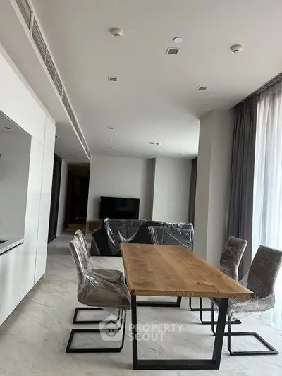 Modern dining area with sleek table and chairs in a spacious open-plan living room.
