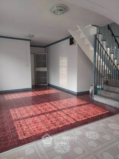 Spacious empty living room with staircase and tiled flooring