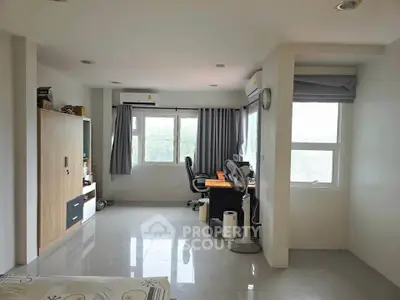 Spacious modern bedroom with study area and large windows for natural light.