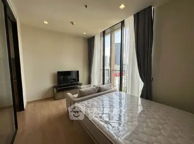 Modern bedroom with large windows and city view, featuring a cozy bed and sleek TV setup.