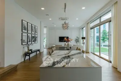 Luxurious open-plan living room with elegant marble island and floor-to-ceiling windows.