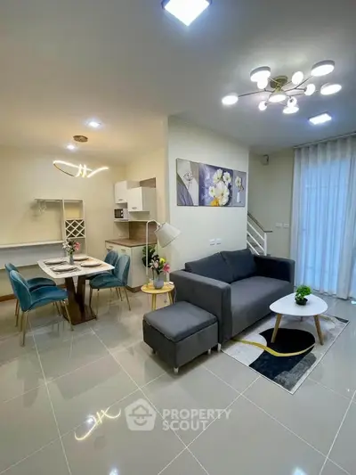 Modern open-plan living room with stylish decor and dining area, featuring elegant lighting and contemporary furniture.