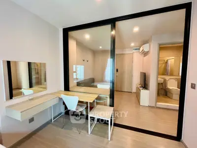 Modern studio apartment with glass partition, sleek furniture, and bright lighting.