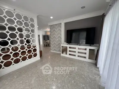 Spacious modern living room with elegant partition and large TV, perfect for family gatherings.