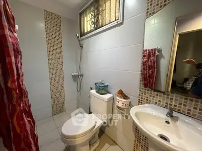 Modern bathroom with shower, toilet, and sink featuring stylish tile accents.