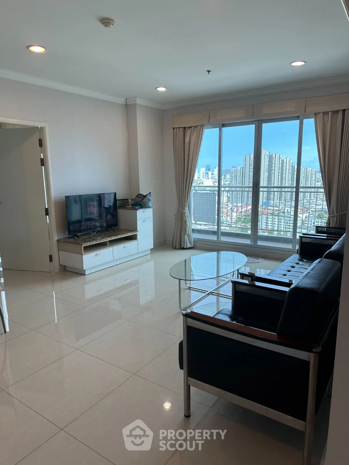 Spacious living room with modern furniture and stunning city view from large windows.