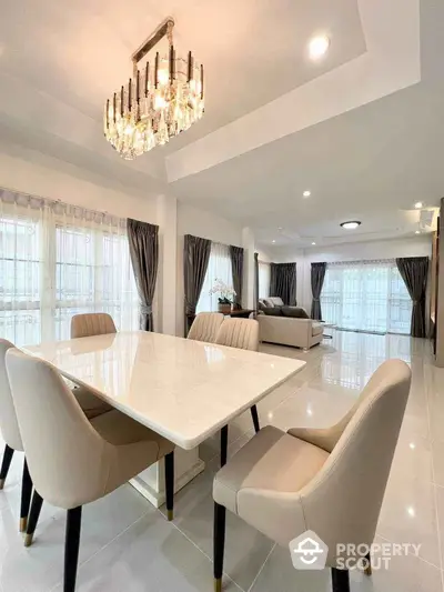 Luxurious open-plan living and dining area with elegant chandelier and modern furnishings.