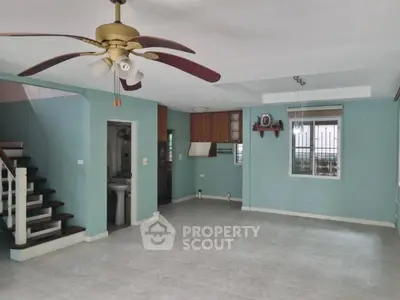 Spacious living room with ceiling fan and staircase in modern home