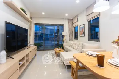Modern living room with stylish decor and large TV, open to a spacious balcony.