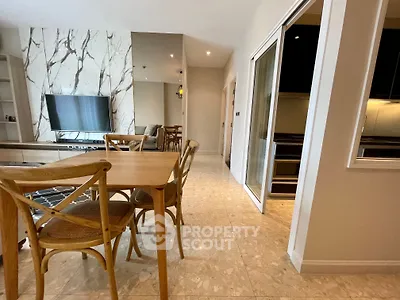 Modern open-plan living and dining area with stylish wooden furniture and marble accents.