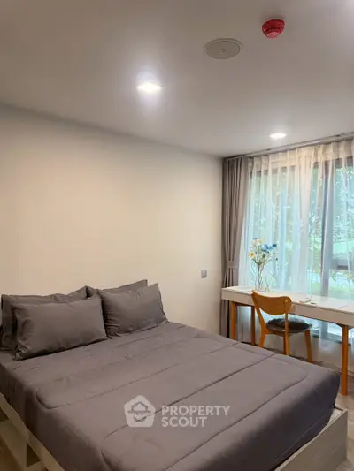 Cozy bedroom with modern decor and natural light from large window, perfect for relaxation.