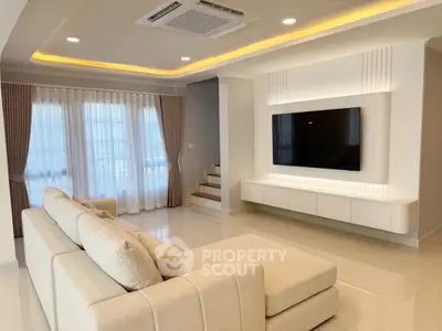 Spacious modern living room with elegant lighting and large TV setup, perfect for relaxation and entertainment.