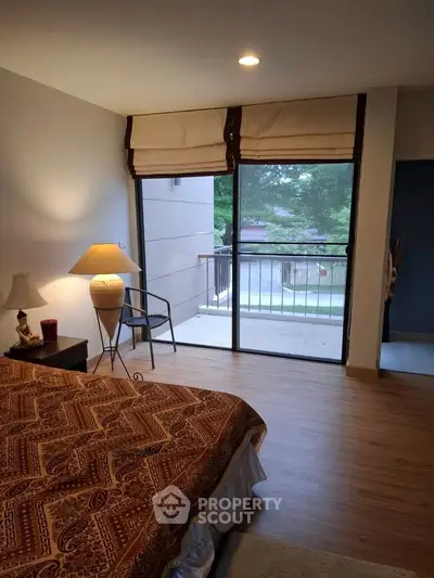 Cozy bedroom with balcony view, featuring elegant decor and natural light.