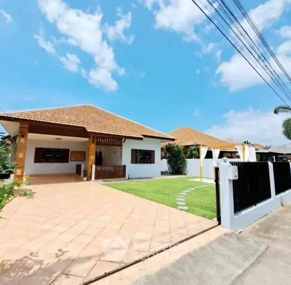 Charming single-story house with spacious driveway and lush green lawn under clear blue sky.