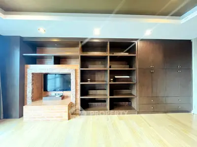 Spacious living room with built-in wooden shelves and brick fireplace, perfect for cozy gatherings.