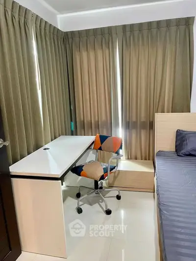 Cozy study area with modern desk and colorful chair in a well-lit room, perfect for productivity.