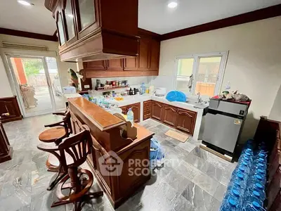 Spacious kitchen with wooden cabinetry and bar seating, featuring modern appliances and ample natural light.
