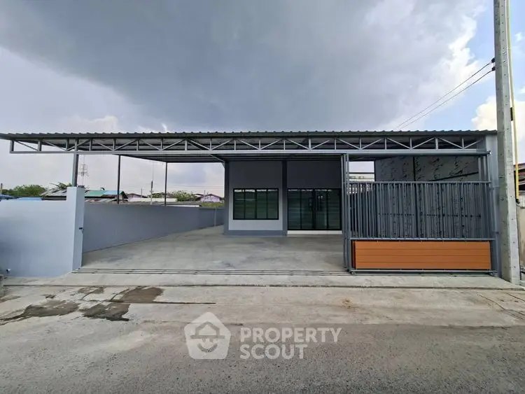 Modern industrial-style building with spacious driveway and metal gate, perfect for commercial use.