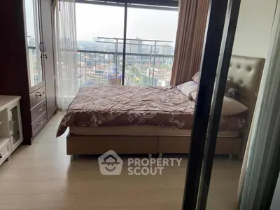 Cozy bedroom with large window offering stunning city view, featuring elegant decor and ample natural light.