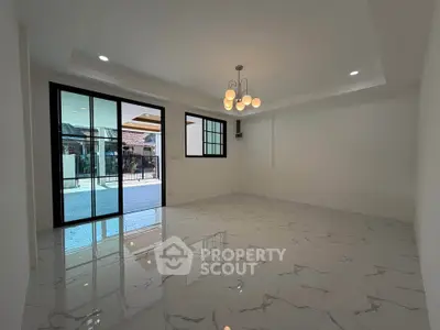 Spacious modern living room with elegant lighting and large sliding glass doors opening to a patio.