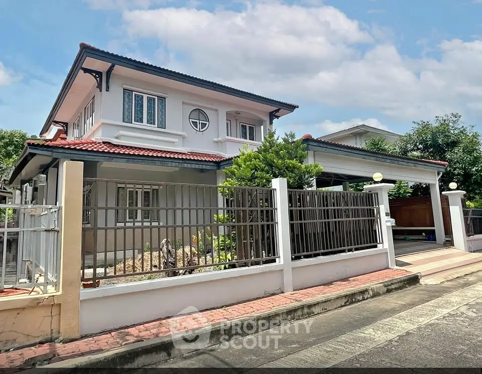 Charming two-story house with red-tiled roof and fenced yard in a serene neighborhood.