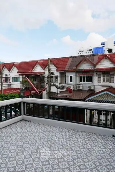 Charming balcony with patterned tiles overlooking quaint neighborhood rooftops.