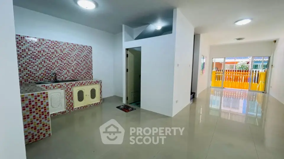 Spacious open-plan living area with modern kitchen and vibrant tile backsplash.