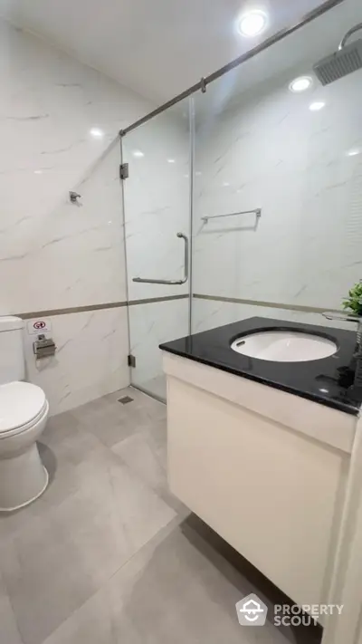 Modern bathroom with glass shower and sleek vanity in a contemporary home.