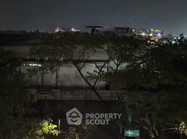 Nighttime view of urban landscape with trees and distant city lights.