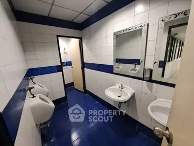 Spacious public bathroom with blue and white tiles, featuring urinals and sinks.