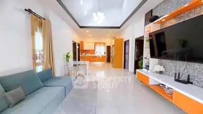 Spacious modern living room with open kitchen, stylish decor, and large TV setup, perfect for family gatherings.