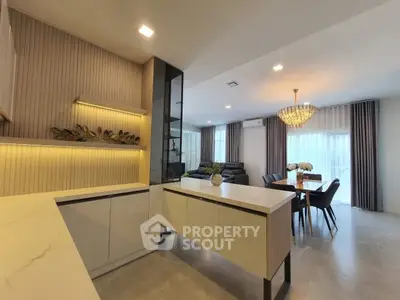 Modern open-plan kitchen and living area with elegant chandelier and stylish decor.