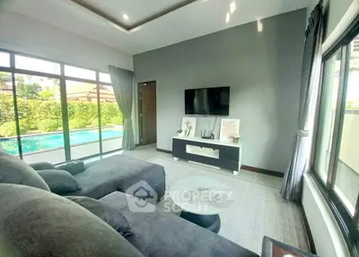 Luxurious living room with pool view, featuring modern decor and large windows for natural light.