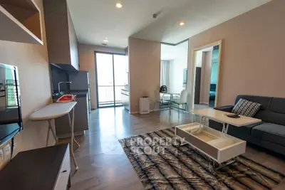 Modern living room with open kitchen and stylish decor in a high-rise apartment.