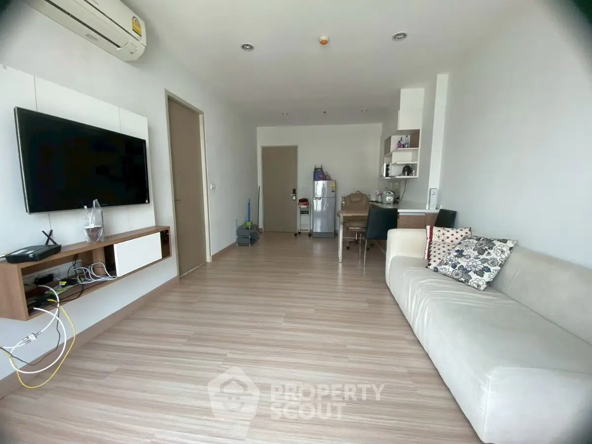 Spacious modern living room with sleek wooden flooring and wall-mounted TV.