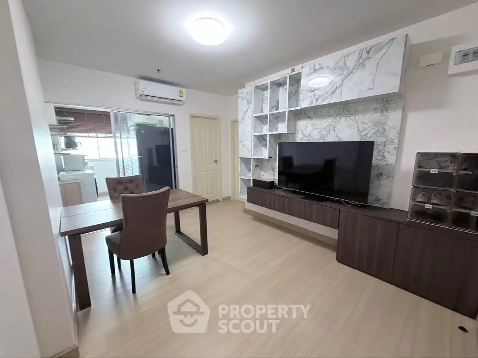 Modern living room with stylish TV unit and dining area in open layout apartment.