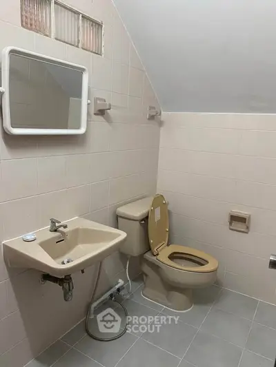 Cozy bathroom with beige fixtures and wall-mounted mirror in a tiled setting.
