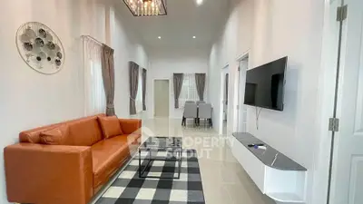 Spacious modern living room with leather sofa and wall-mounted TV in a stylish home.