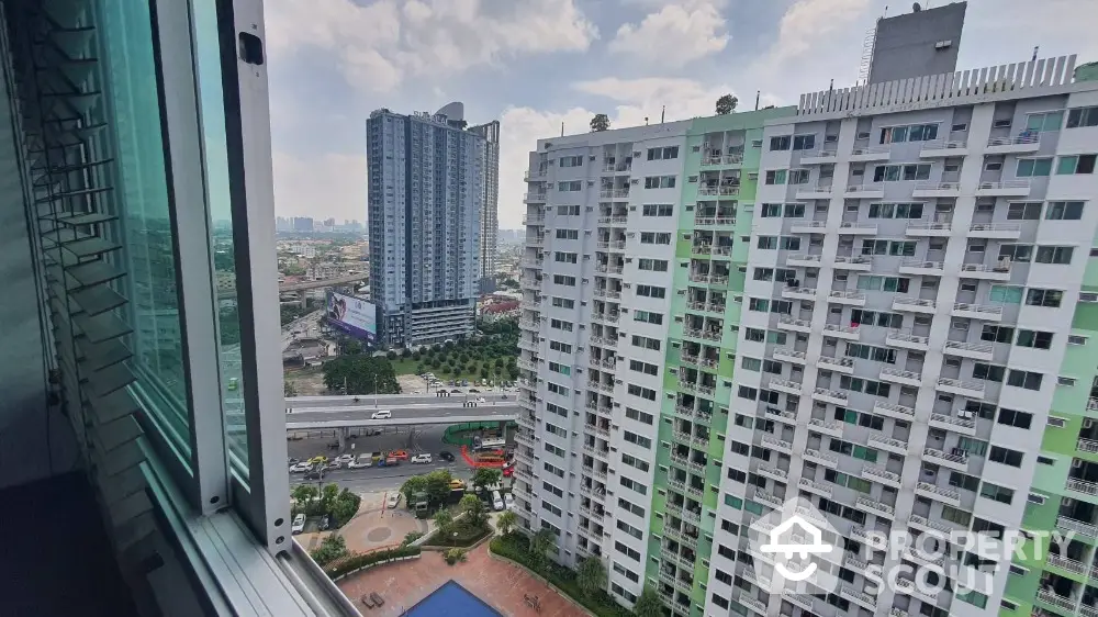 Stunning cityscape view from high-rise apartment window overlooking urban skyline and pool area.