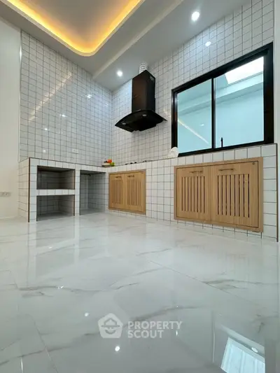 Modern kitchen with sleek tile design and ample natural light, featuring a stylish range hood and wooden cabinetry.