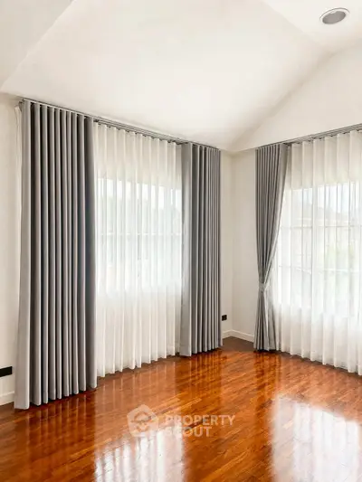 Spacious corner unit with elegant floor-to-ceiling windows and luxurious curtains.