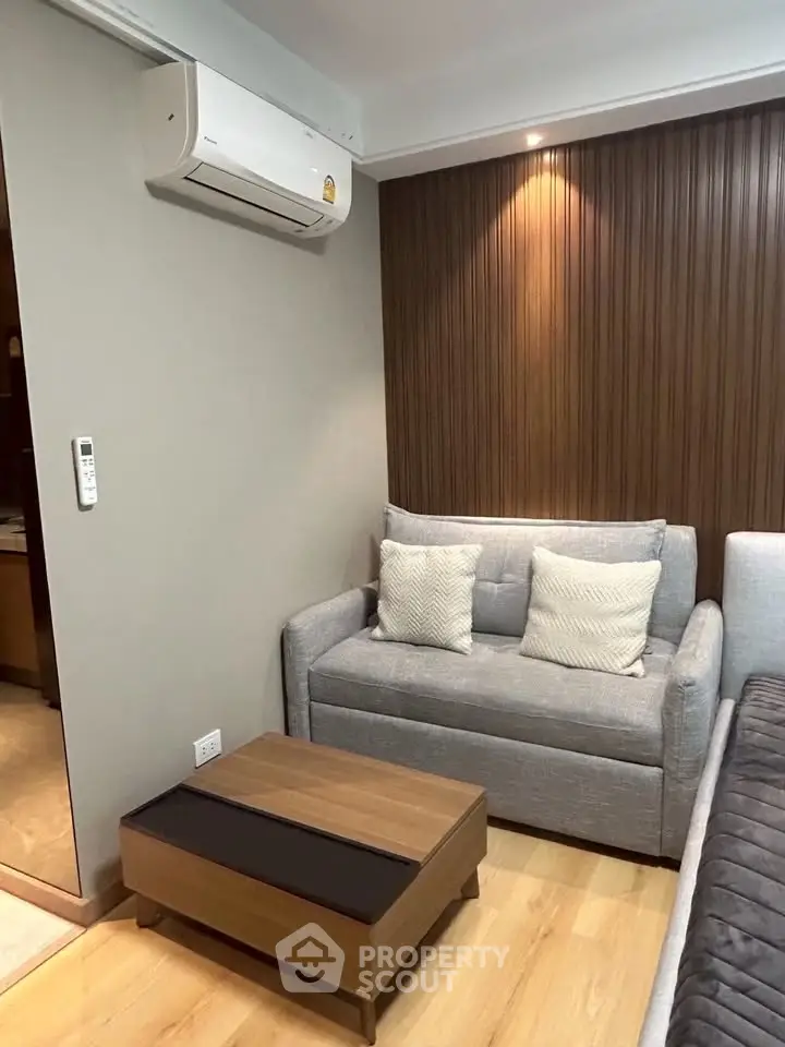 Cozy living room with modern sofa, wooden accent wall, and air conditioning unit.