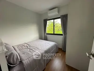 Cozy bedroom with large window and air conditioning, featuring a comfortable bed and elegant curtains.