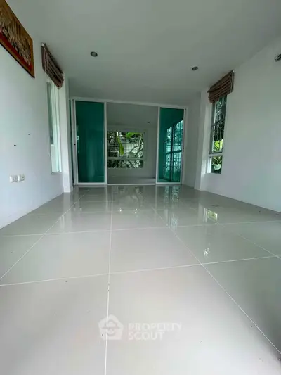 Spacious empty room with glossy tiled floor and large windows, perfect for customization.