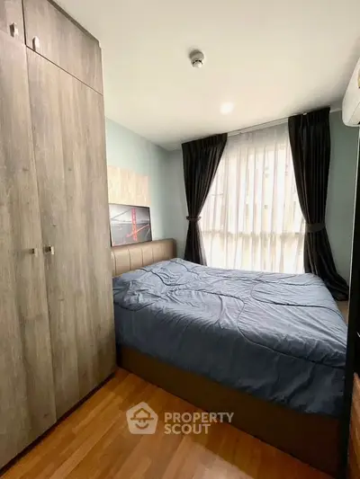 Cozy bedroom with modern decor, large window, and wooden flooring in a stylish apartment.