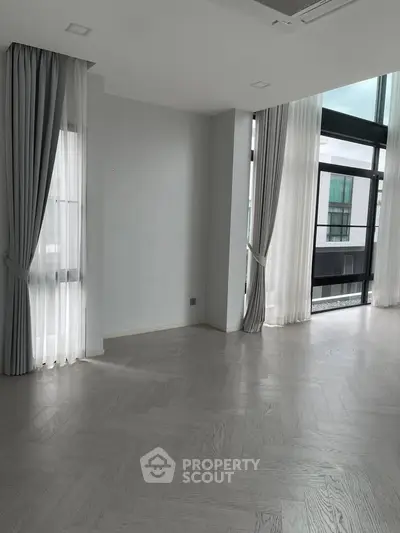 Spacious modern living room with large windows and elegant curtains.