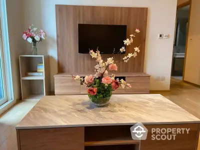 Elegantly designed living space with modern wooden entertainment unit and a stylish coffee table adorned with a floral arrangement.