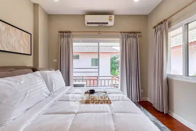 Cozy bedroom with large bed, elegant curtains, and a view of neighboring house through window.