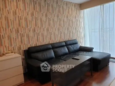 Modern living room with stylish wallpaper and comfortable black leather sofa.