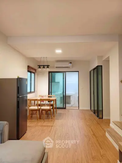 Spacious open-plan living area with modern kitchen and dining space, featuring wooden flooring and ample natural light.